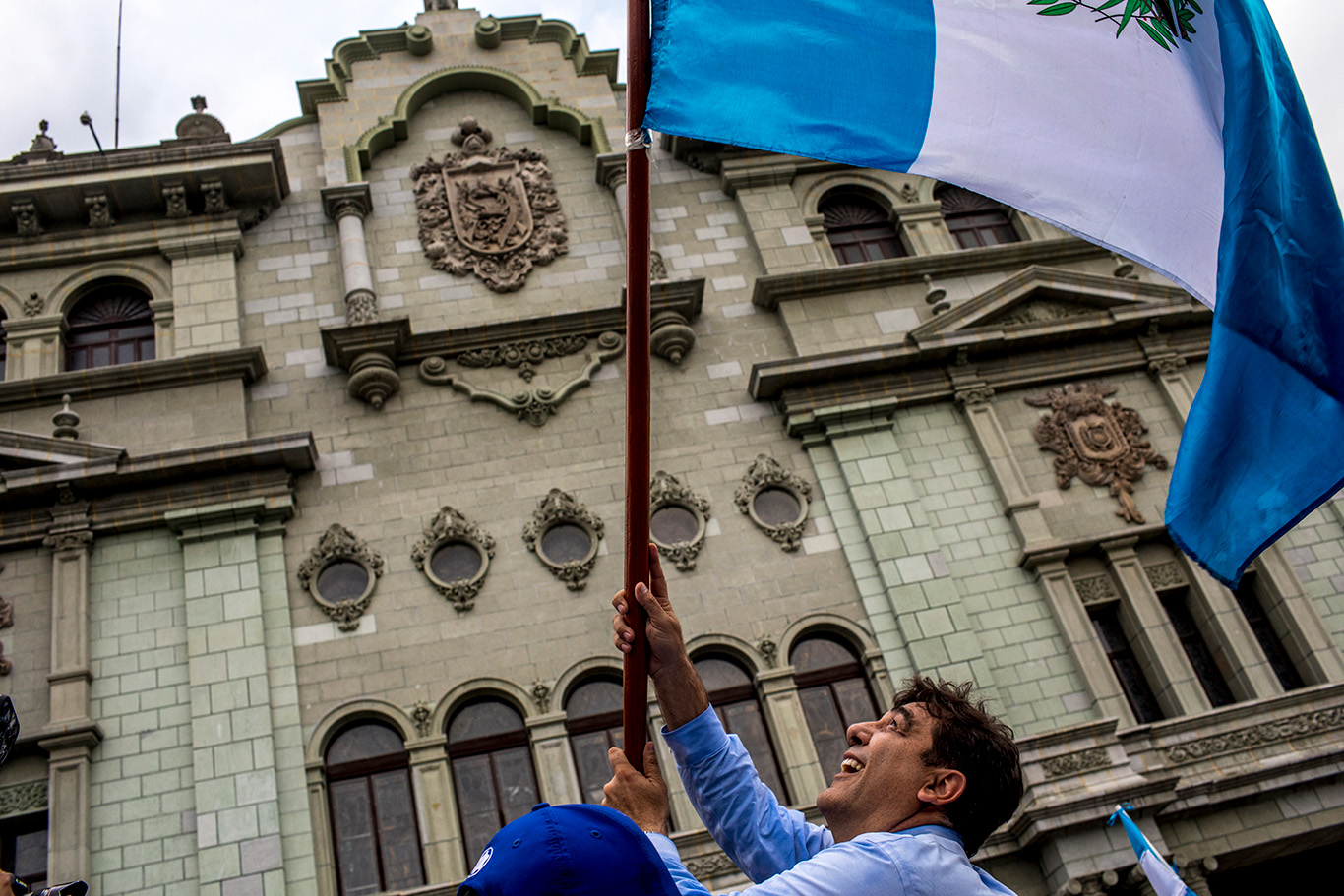Carlos Pineda ondea la bandera nacional frente al Palacio Nacional, rodeado de simpatizantes y curiosos