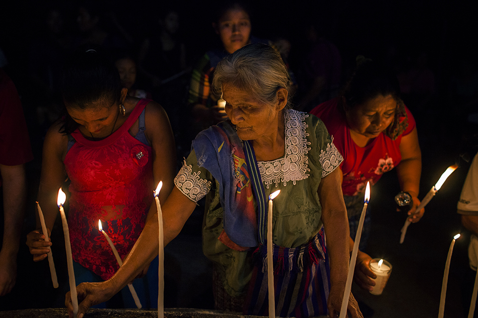 Una anciana enciende unas velas en recuerdo a los familiares caídos en la masacre de Cuarto Pueblo.