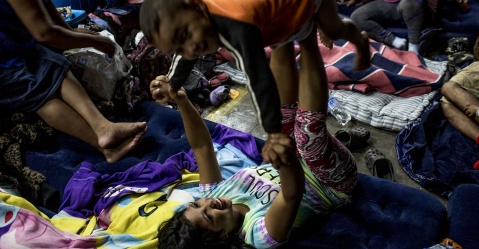Yoselin Mabel Vargas, 17, juega con su hermano Manuel, de 3 años, antes de dormirse en las instalaciones del colegio Santa María, donde pasará la noche junto con su madre y dos hermanas más Simone Dalmasso