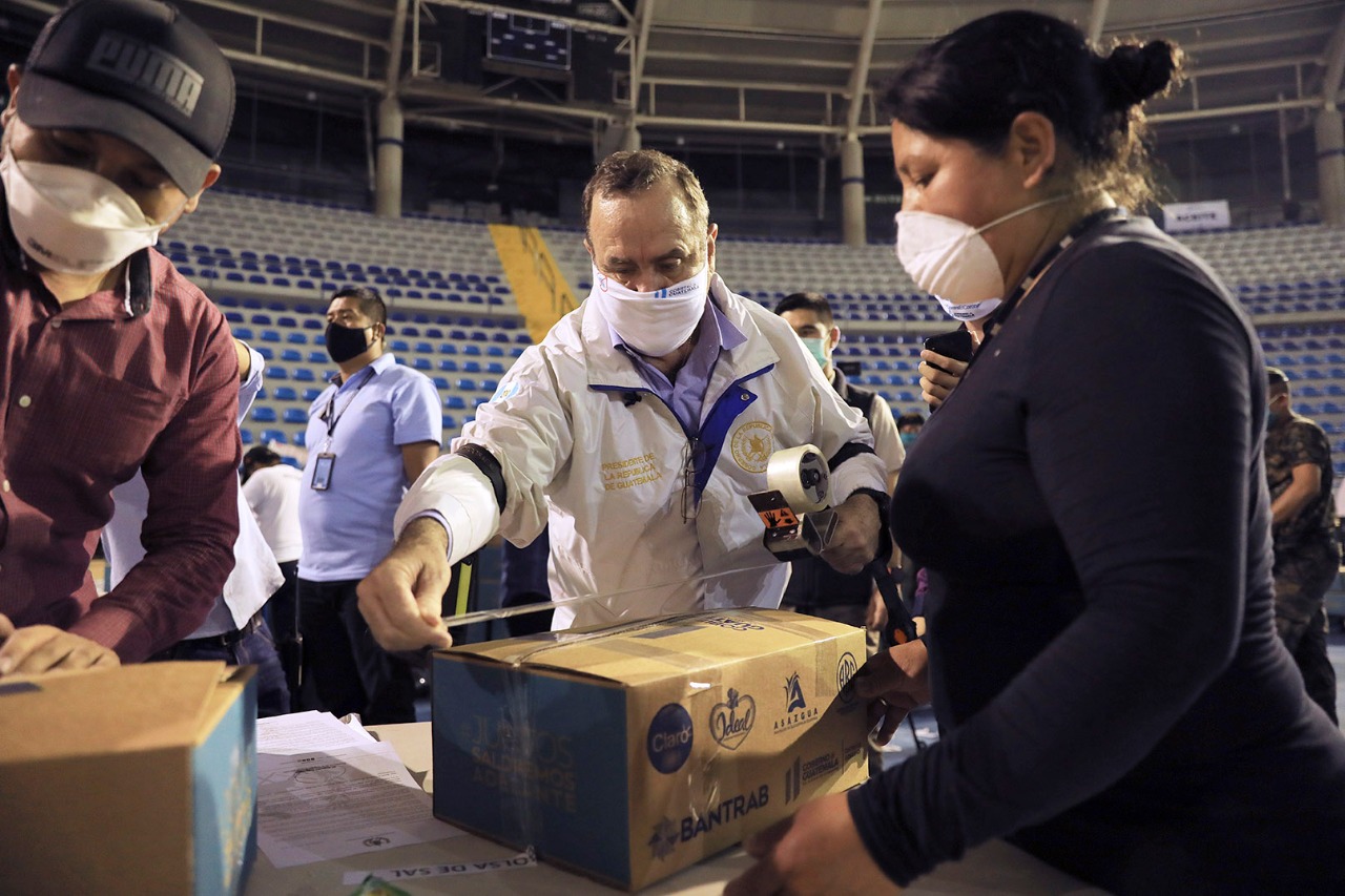 El presidente de la República, Alejandro Giammattei ayuda a empacar cajas de alimentos que distribuirán a la población más afectada por la crisis económica del COVID19